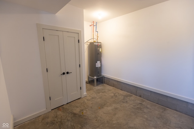 interior space with electric water heater and concrete flooring