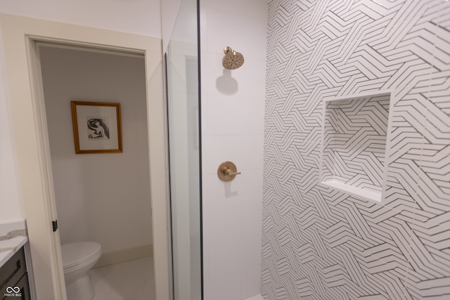 bathroom with tiled shower, vanity, and toilet