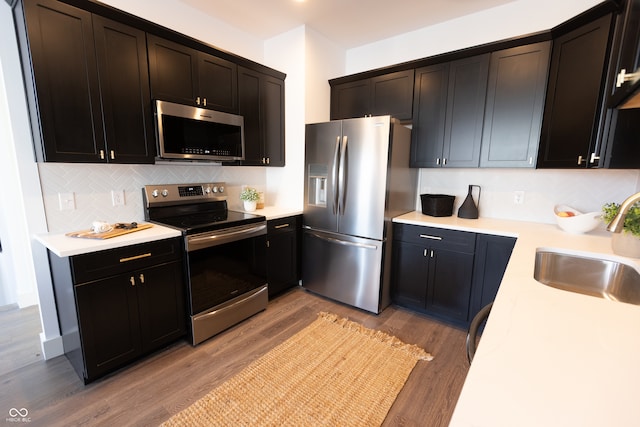 kitchen featuring sink, light hardwood / wood-style flooring, stainless steel appliances, and backsplash