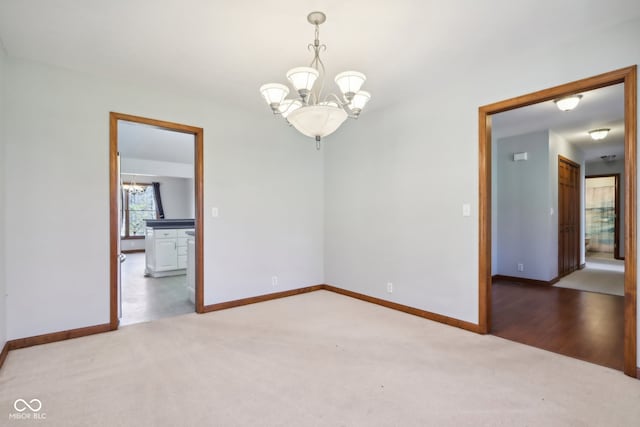 unfurnished room with carpet floors and an inviting chandelier