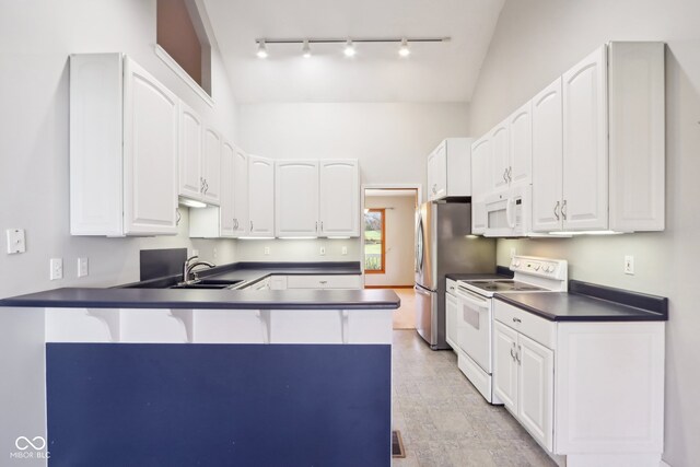 kitchen featuring white cabinets, white appliances, vaulted ceiling, and kitchen peninsula