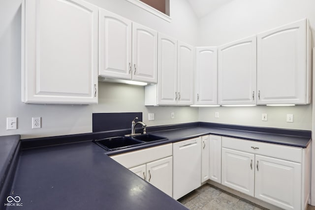 kitchen featuring sink, vaulted ceiling, white dishwasher, and white cabinets