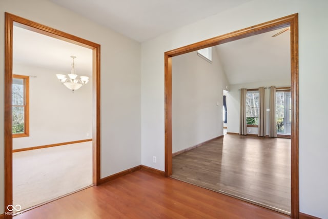 unfurnished room featuring an inviting chandelier and hardwood / wood-style flooring