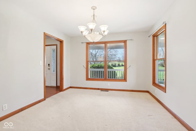 carpeted spare room with a chandelier