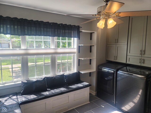 washroom with dark tile patterned floors, washer and dryer, ceiling fan, cabinets, and plenty of natural light