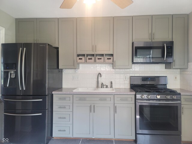 kitchen featuring backsplash, ceiling fan, gray cabinets, appliances with stainless steel finishes, and sink