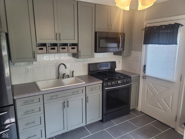 kitchen featuring appliances with stainless steel finishes, dark tile patterned floors, tasteful backsplash, and sink