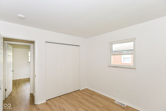 unfurnished bedroom with a closet and light wood-type flooring