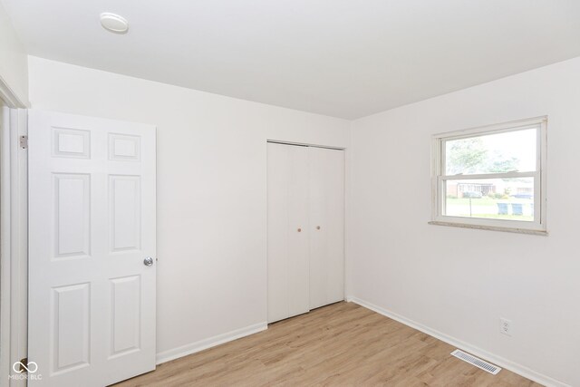 unfurnished bedroom featuring light wood-type flooring and a closet