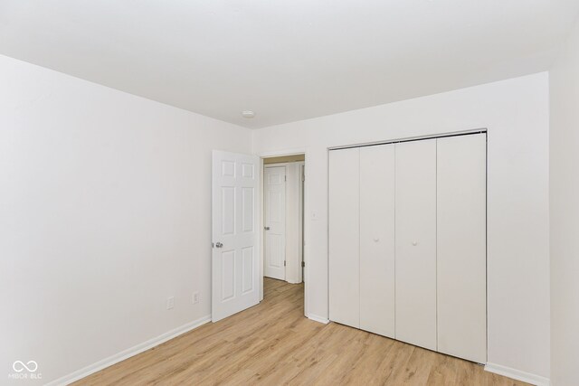 unfurnished bedroom with light hardwood / wood-style flooring and a closet