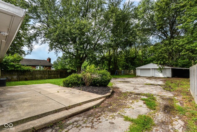 view of yard featuring an outdoor structure, a garage, and a patio area