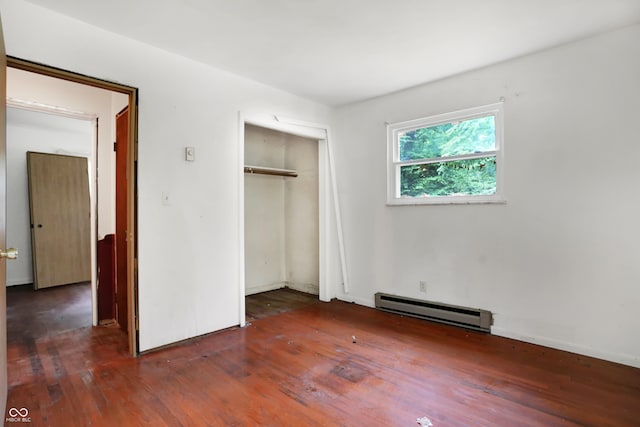 unfurnished bedroom featuring baseboard heating, wood-type flooring, and a closet