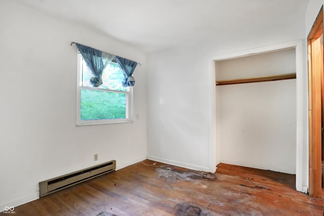 unfurnished bedroom featuring wood-type flooring, baseboard heating, and a closet