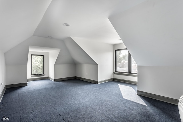 additional living space featuring vaulted ceiling, a wealth of natural light, and dark carpet