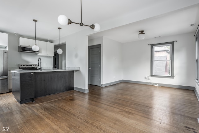 kitchen featuring pendant lighting, appliances with stainless steel finishes, white cabinetry, dark hardwood / wood-style floors, and kitchen peninsula