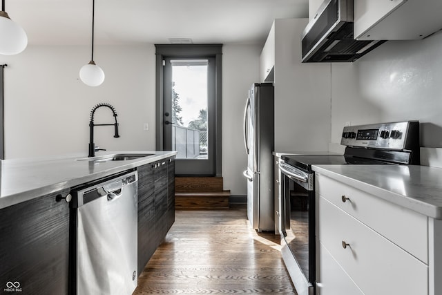 kitchen with pendant lighting, sink, dark wood-type flooring, appliances with stainless steel finishes, and white cabinetry