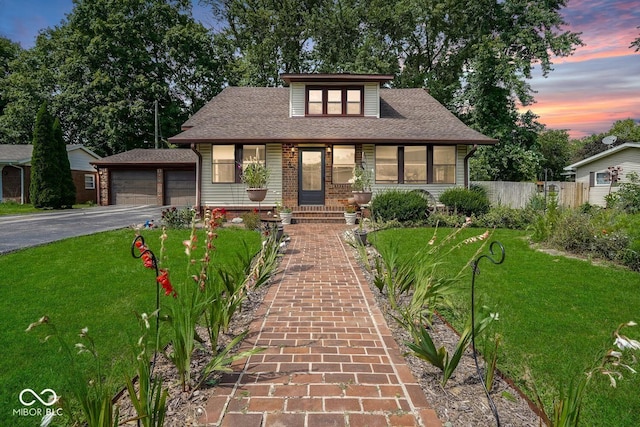 view of front of property with a garage, a yard, and an outbuilding