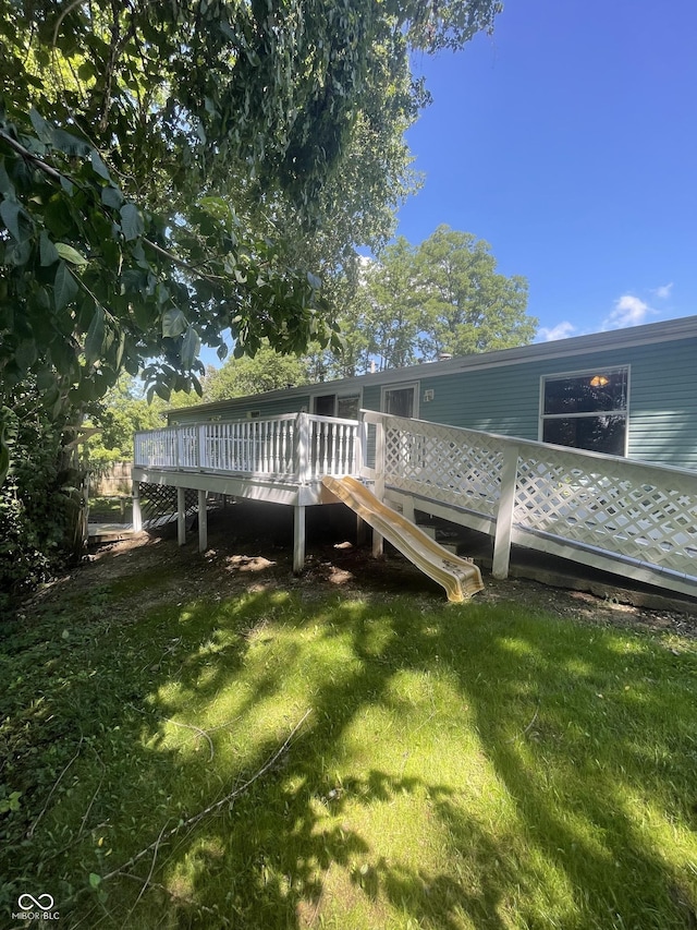 rear view of house featuring a wooden deck and a yard