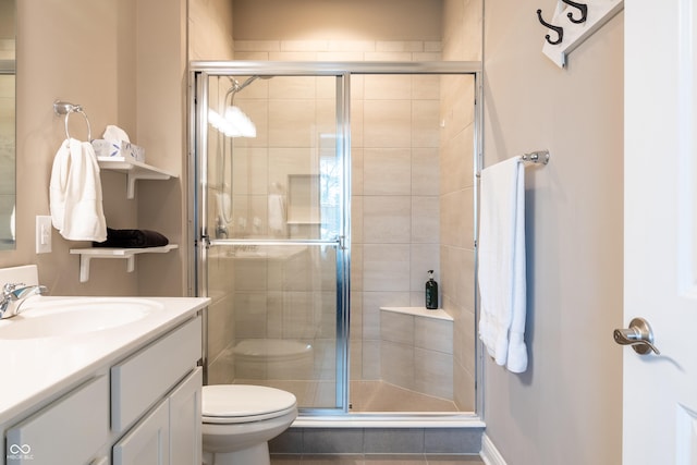 bathroom with vanity, toilet, and a shower with shower door