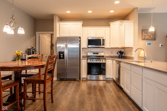 kitchen with pendant lighting, sink, white cabinets, dark hardwood / wood-style flooring, and stainless steel appliances