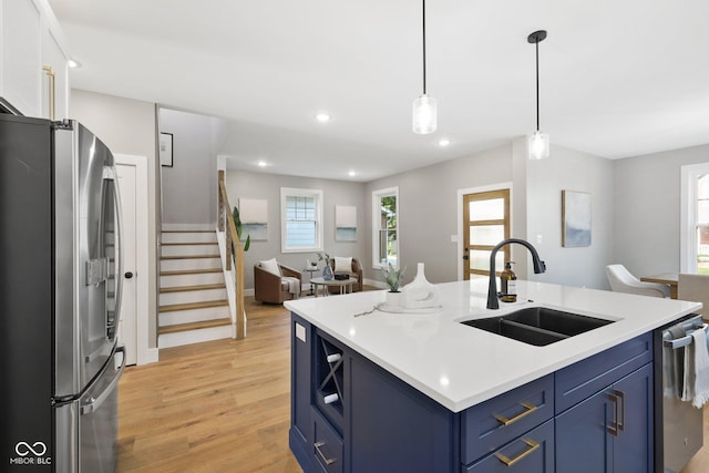 kitchen with blue cabinetry, sink, a center island with sink, pendant lighting, and stainless steel appliances