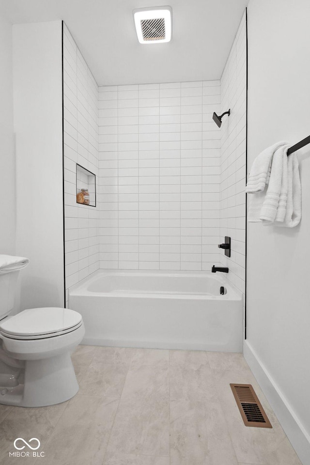 bathroom featuring tiled shower / bath combo and toilet