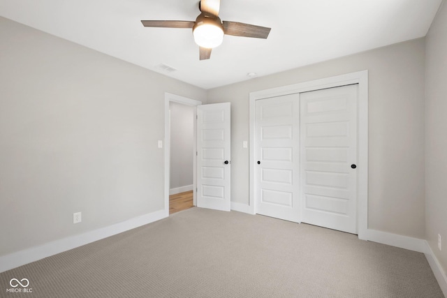 unfurnished bedroom featuring ceiling fan, light colored carpet, and a closet