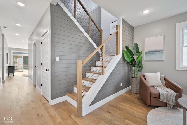 stairway with hardwood / wood-style floors, a wealth of natural light, and wooden walls