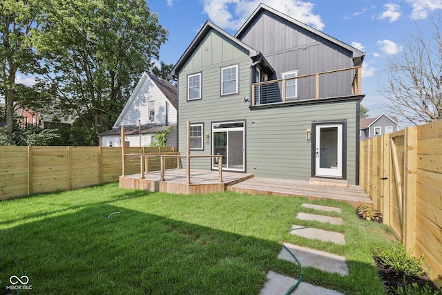 rear view of house featuring a deck and a lawn