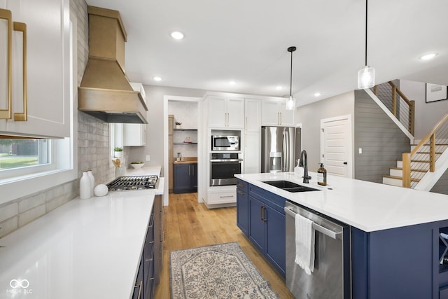 kitchen with blue cabinetry, premium range hood, sink, white cabinetry, and appliances with stainless steel finishes