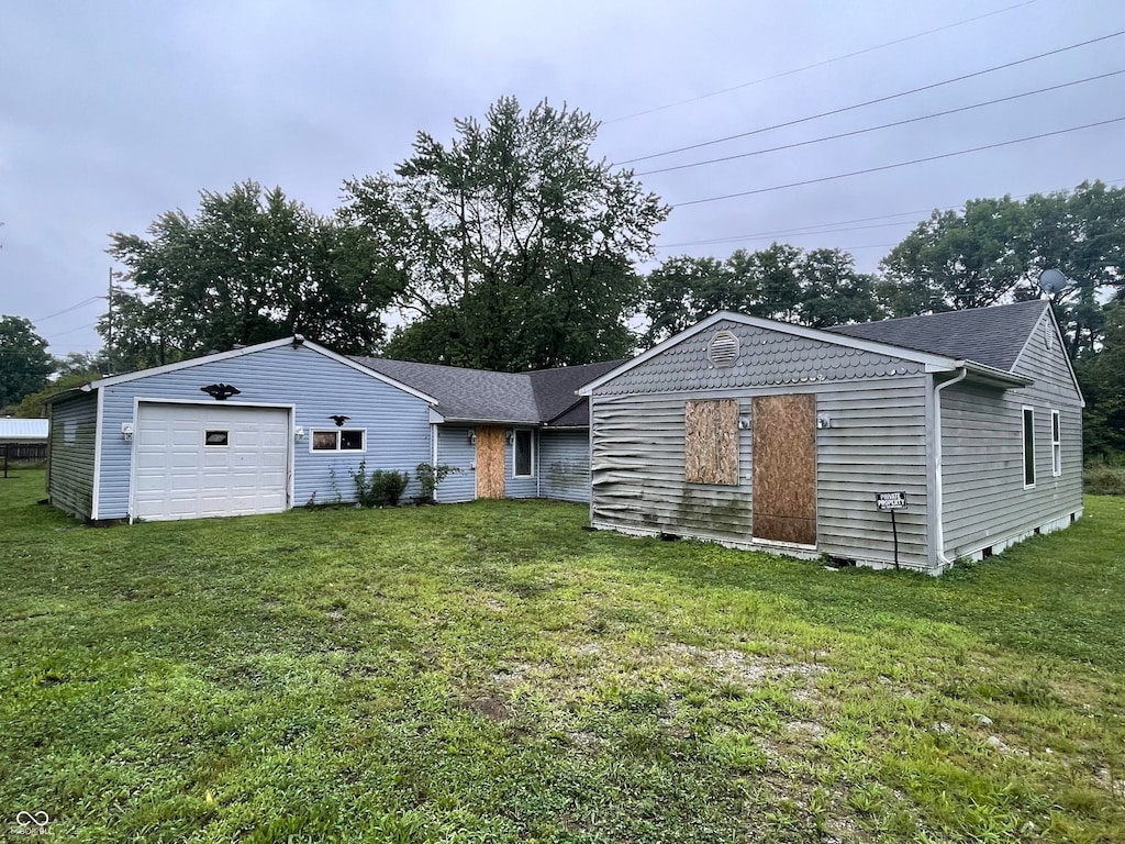 back of property with a garage and a lawn