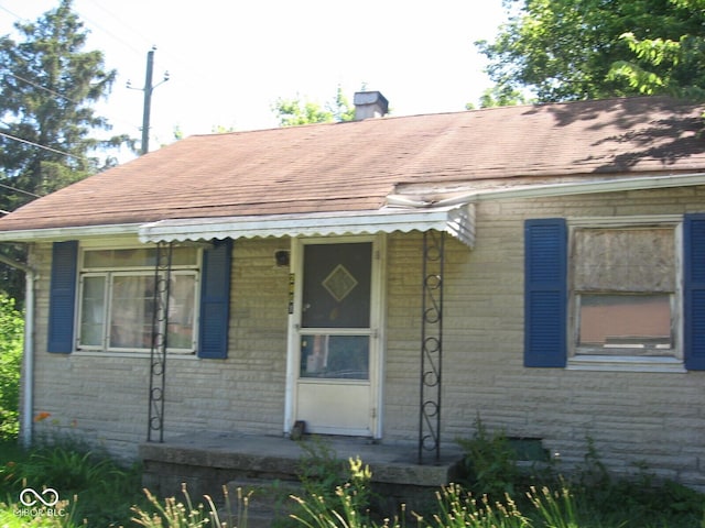 view of front of home with a shingled roof and a chimney