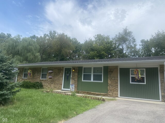 ranch-style house featuring stone siding and driveway