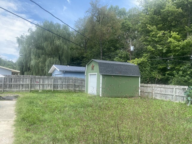 view of yard featuring a fenced backyard, a shed, and an outbuilding