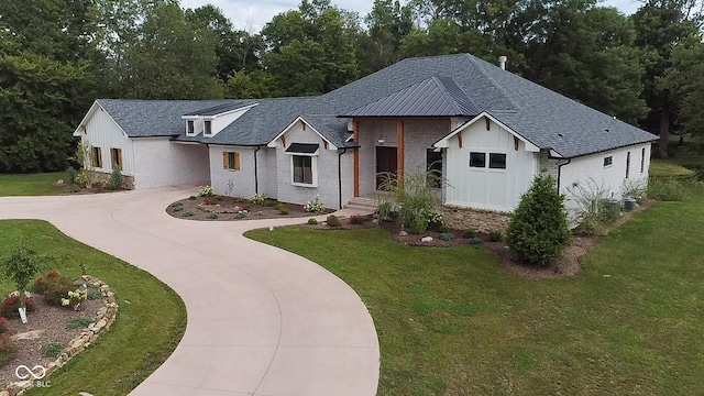 modern farmhouse style home with board and batten siding, brick siding, concrete driveway, and a front yard