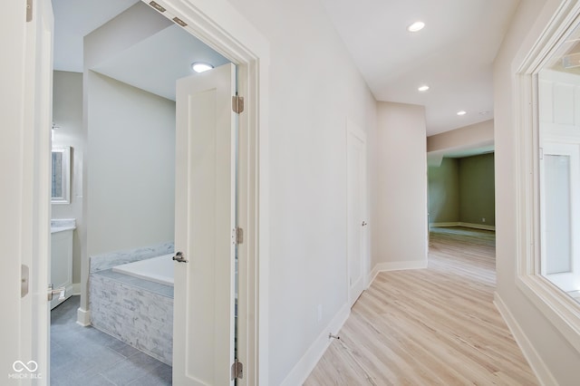 hallway with light wood-type flooring, baseboards, and recessed lighting