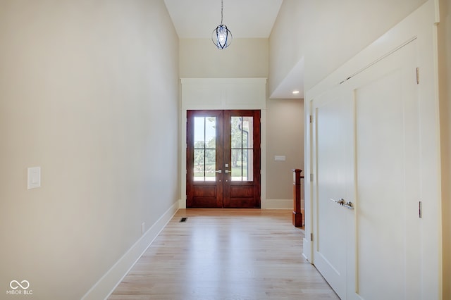 entryway featuring french doors, light wood-type flooring, and a high ceiling