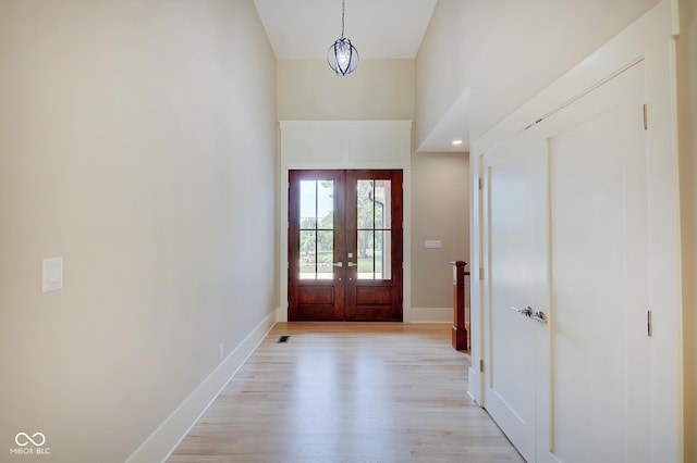 entrance foyer with french doors, visible vents, a towering ceiling, light wood-style floors, and baseboards