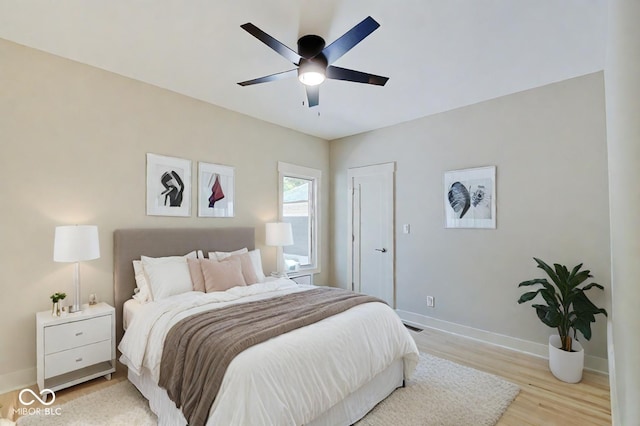bedroom with light wood-style floors, visible vents, baseboards, and a ceiling fan