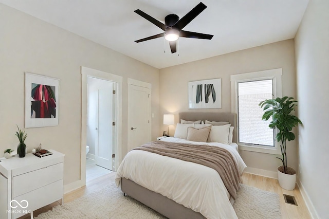 bedroom featuring light wood-type flooring, ceiling fan, and connected bathroom