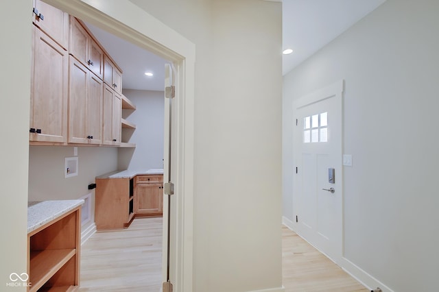 washroom featuring cabinet space, baseboards, washer hookup, and light wood finished floors