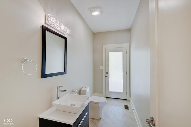 bathroom with baseboards, vanity, and toilet