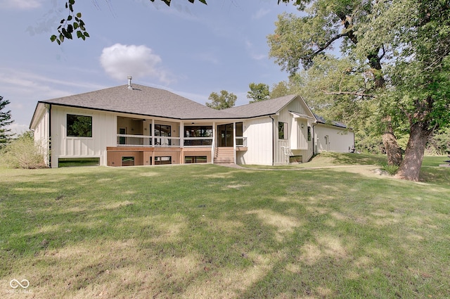 rear view of property with board and batten siding, roof with shingles, and a yard