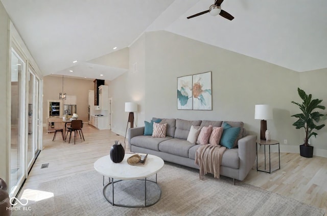 living room featuring high vaulted ceiling, light hardwood / wood-style flooring, a wealth of natural light, and ceiling fan