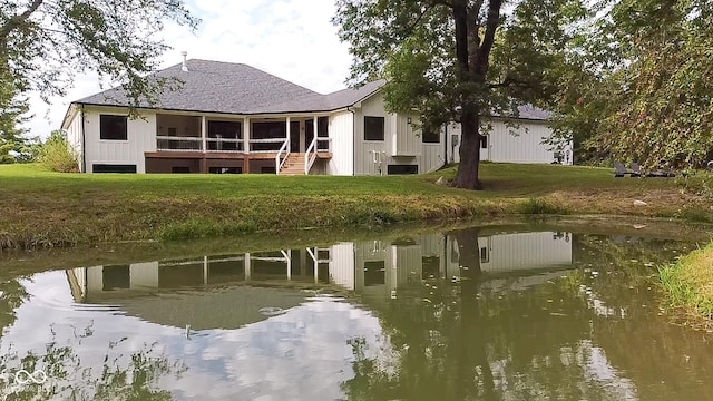 exterior space featuring a sunroom, a water view, and a lawn