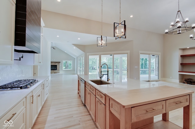 kitchen featuring light hardwood / wood-style flooring, white cabinets, a stone fireplace, and backsplash