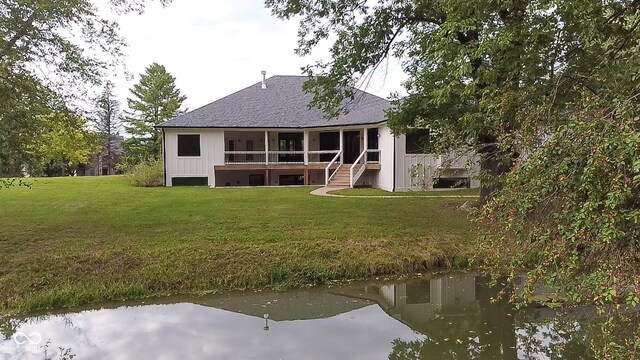 rear view of property with board and batten siding, a sunroom, stairs, and a lawn