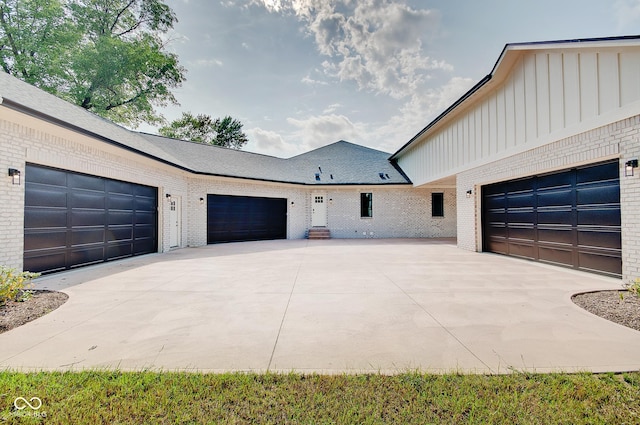 view of side of property featuring board and batten siding, a garage, concrete driveway, and brick siding