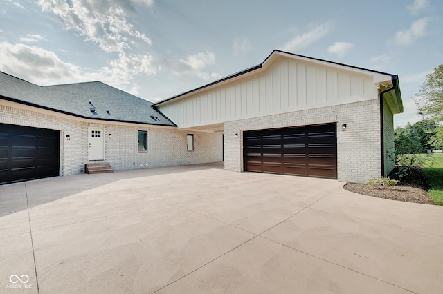 view of front of property with an attached garage, driveway, board and batten siding, and brick siding