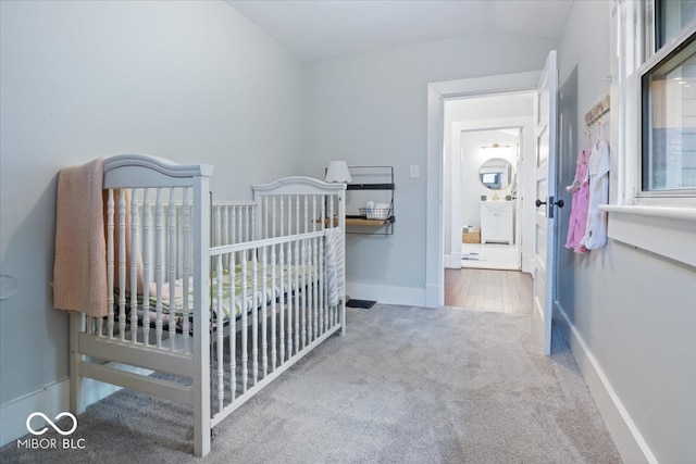 bedroom with a crib, vaulted ceiling, and hardwood / wood-style floors